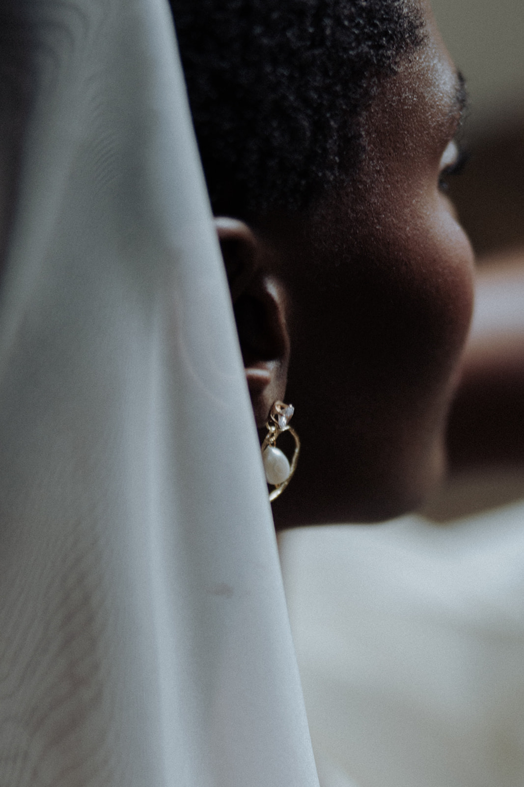 Close-up bridal jewellery beneath veil, modern editorial detail.