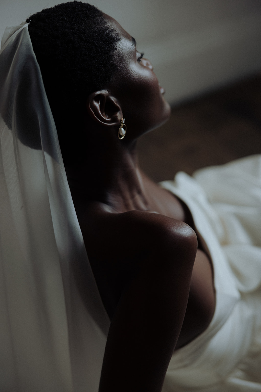 Bride reclining with veil and couture gown, modern editorial bridal portrait.