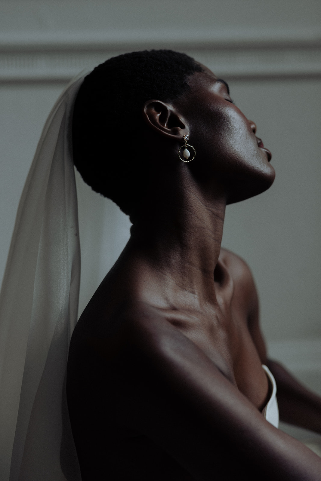 Bride in veil with luminous earrings, close-up editorial bridal detail.