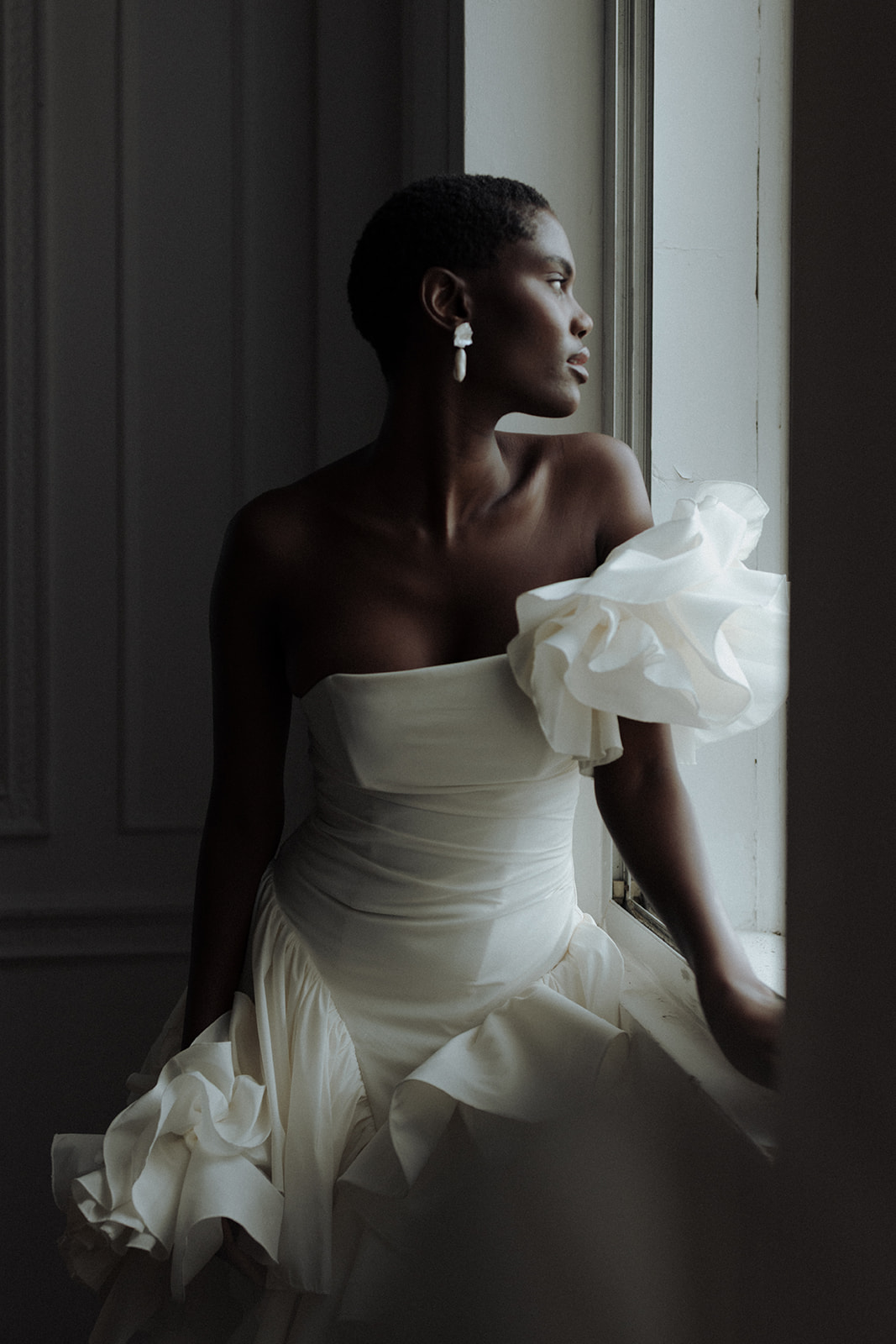 Bride in asymmetric Darla Haute Couture gown, dramatic editorial shadow portrait.
