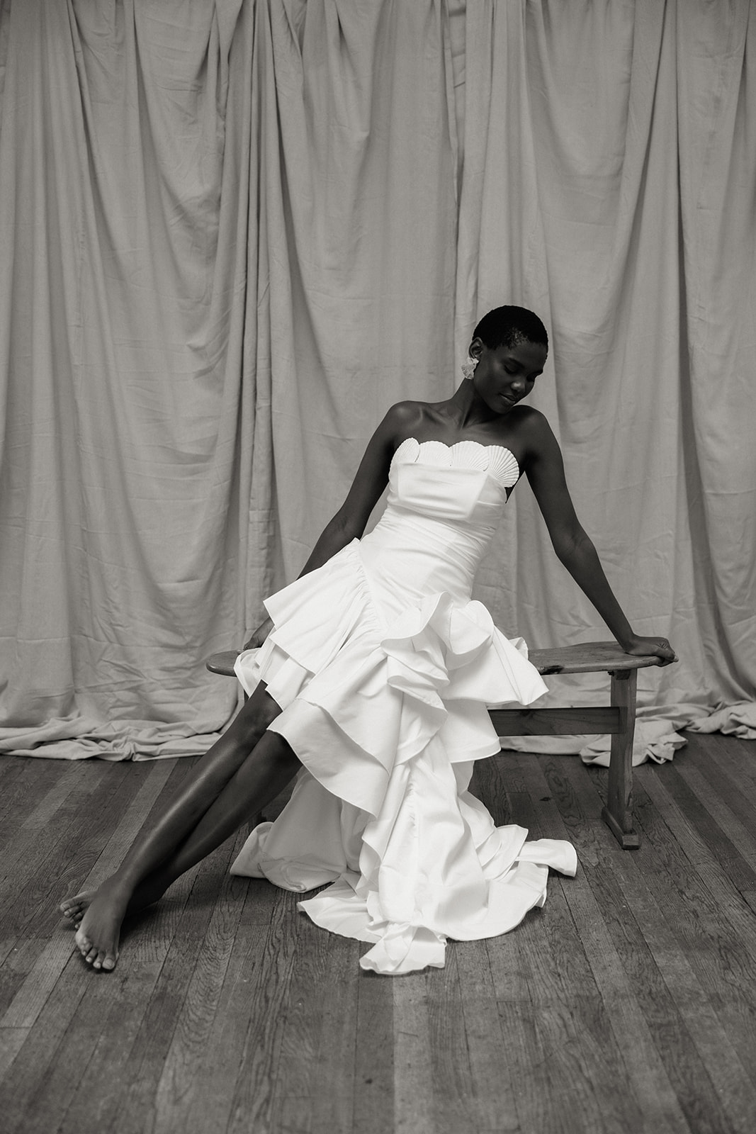 Bride in strapless Darla Haute Couture gown leaning on stool, editorial bridal fashion portrait.