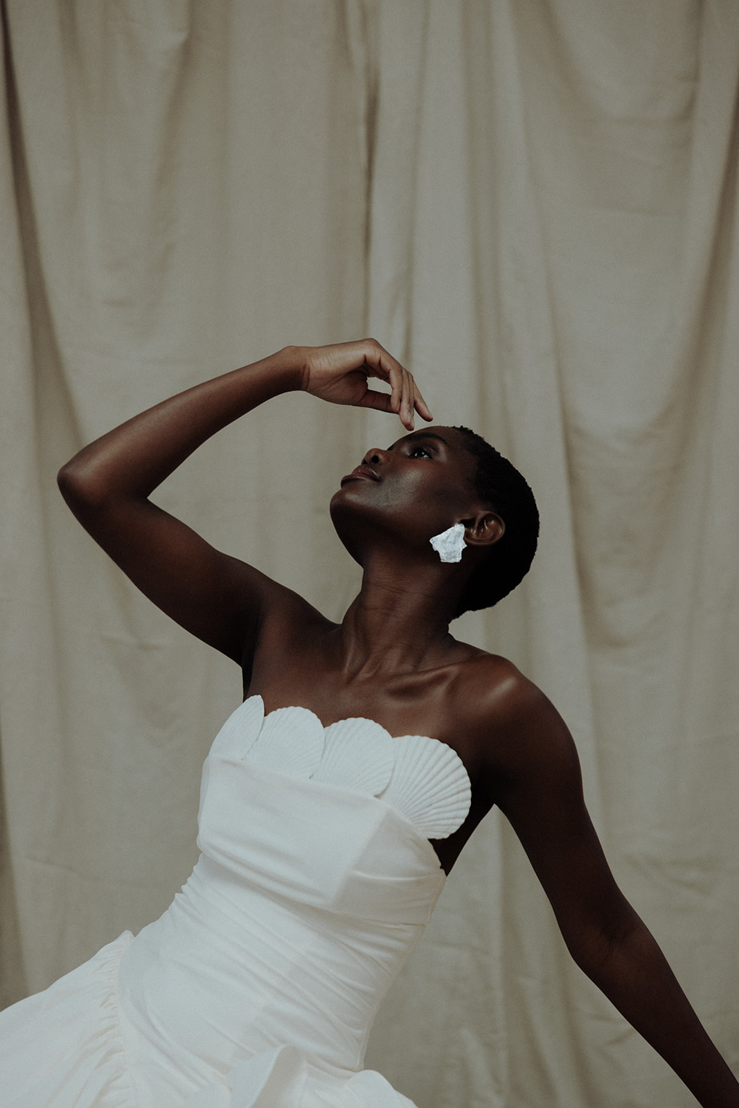 Bride in strapless couture gown, hand raised, editorial bridal portrait
