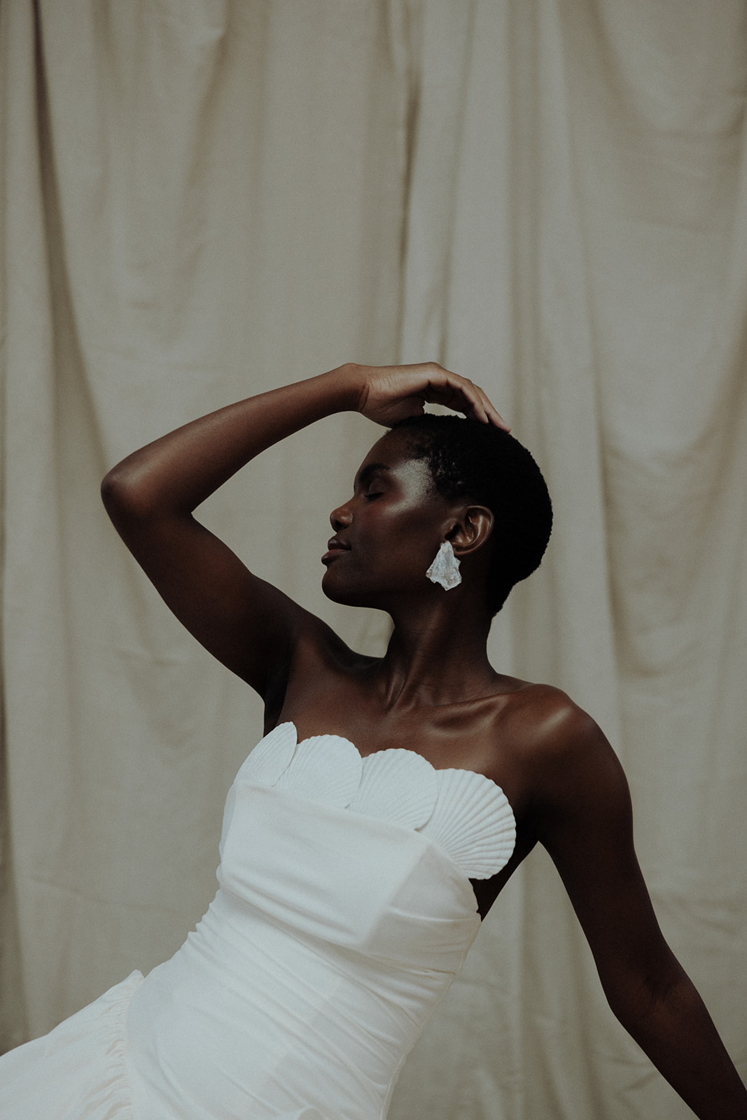 Bride in strapless Darla Haute Couture gown, side profile with raised hand, editorial bridal photograph.