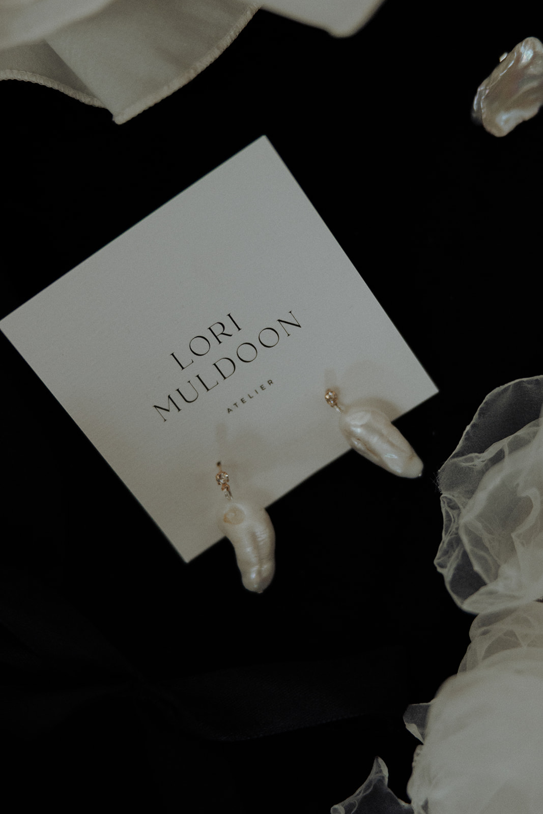 Bridal earrings by Lori Muldoon styled with branded card, editorial jewellery photograph.