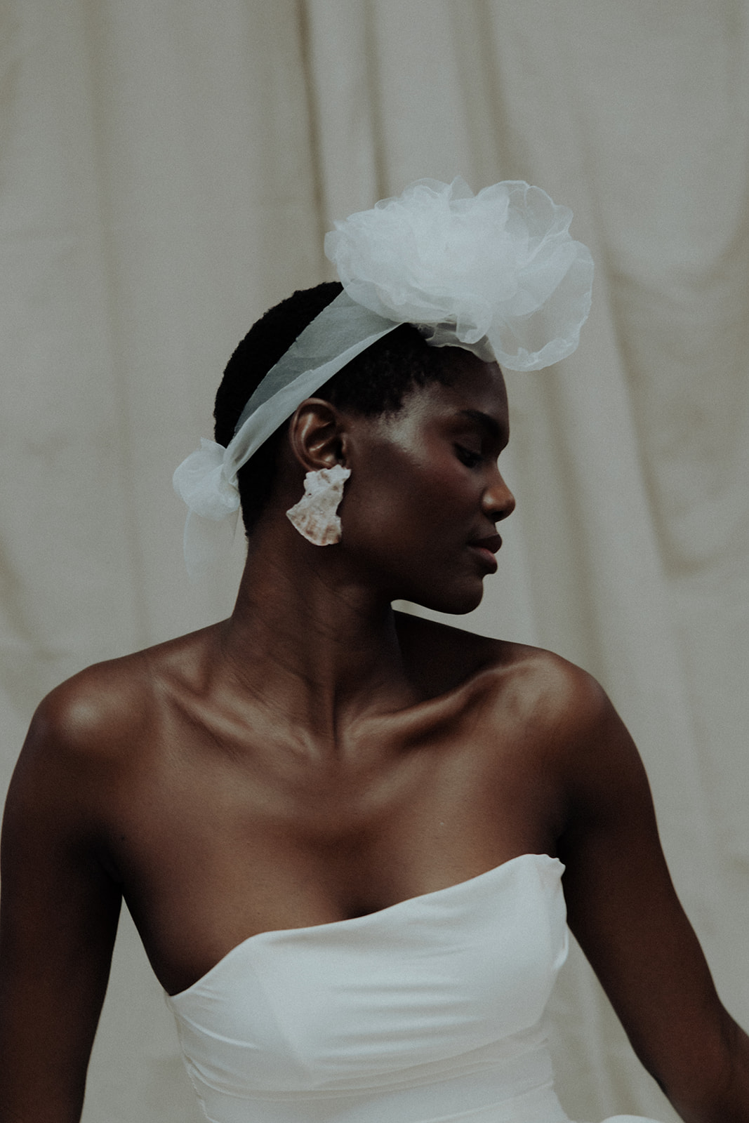 Bride in strapless Darla Haute Couture gown with headpiece and statement earrings, editorial bridal portrait.