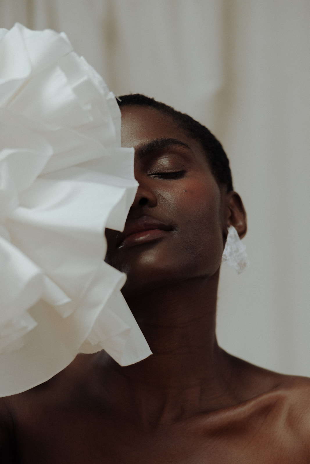 Bride in strapless couture gown with ruffled fabric detail obscuring face, editorial bridal portrait.