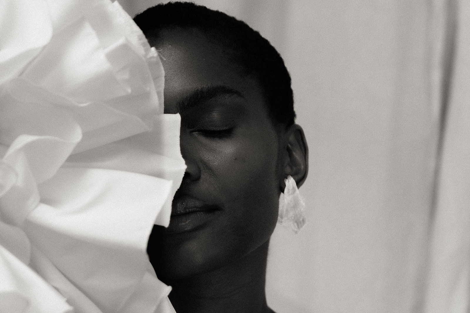 Bride in couture gown with sculptural fabric across face, editorial bridal portrait.