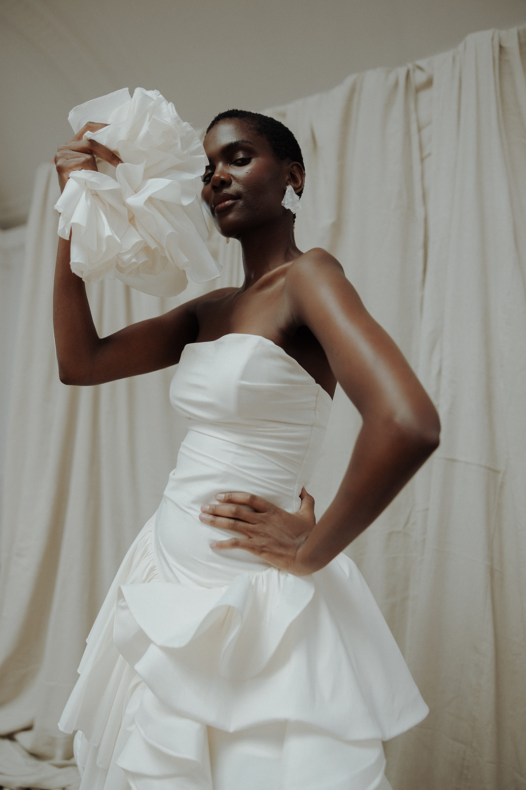 Bride in strapless Darla Haute Couture gown with arm lifted, editorial bridal pose.
