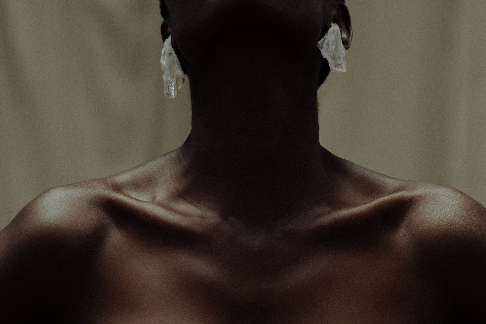 Close-up bridal detail of shoulders and sculptural earrings, editorial wedding photograph.