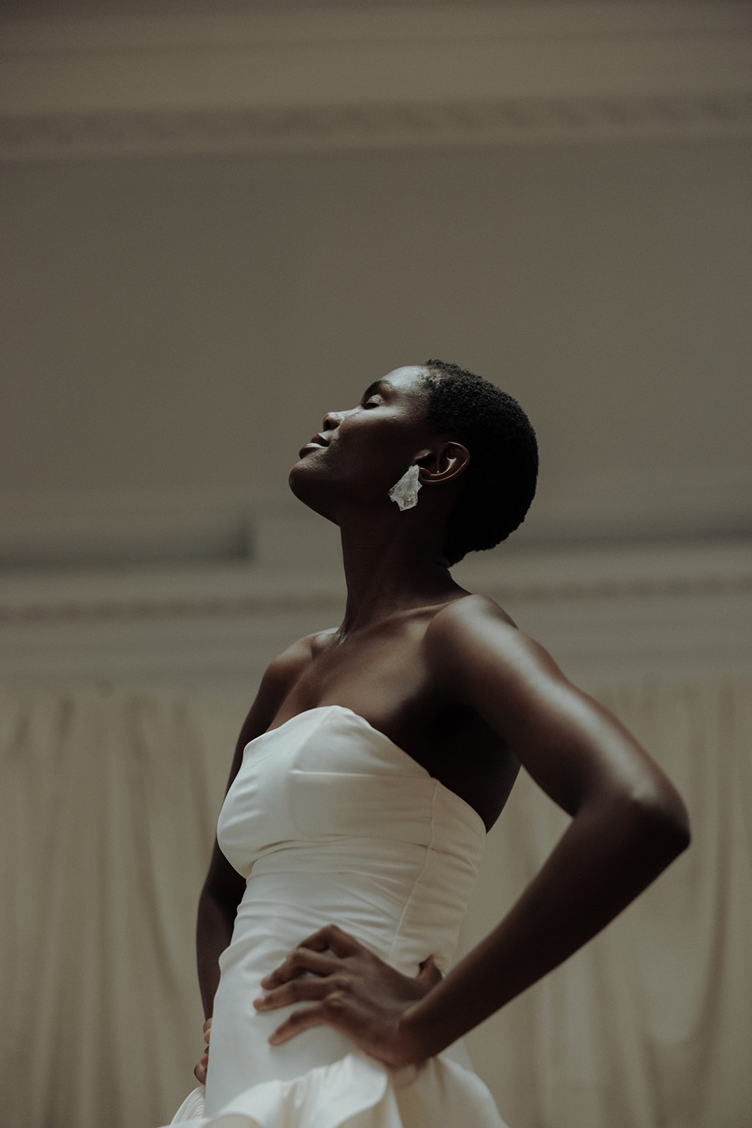 Bride in strapless Darla Haute Couture gown, head tilted back with earrings, editorial portrait.
