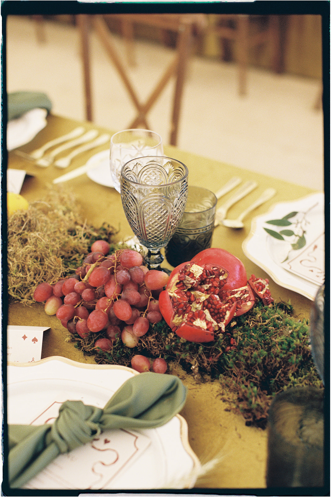 utumnal tablescape styled with pomegranate, grapes, and moss by Tupelo Tree at Winton Castle.