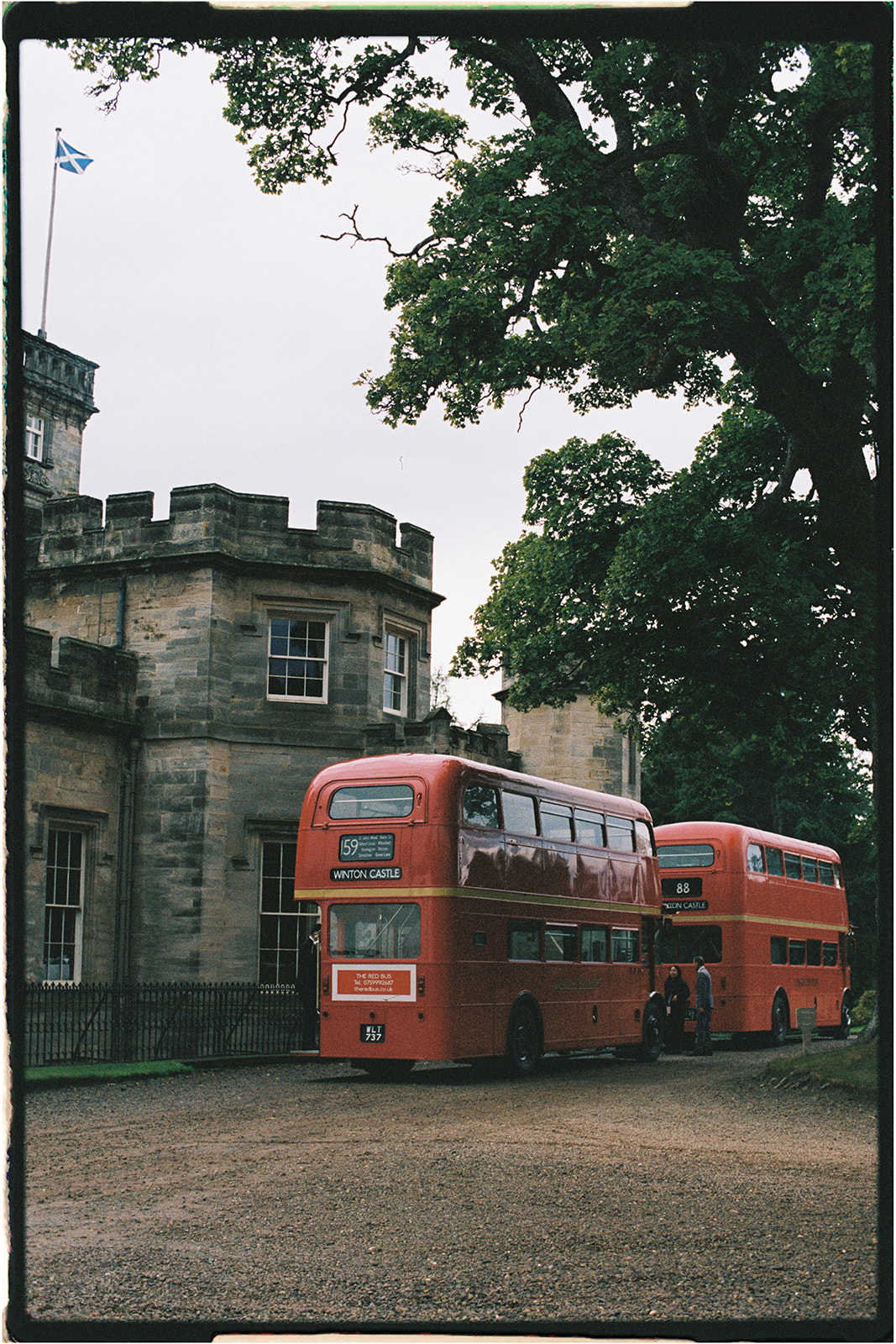 Classic red double-decker wedding bus parked outside Winton Castle in Scotland.