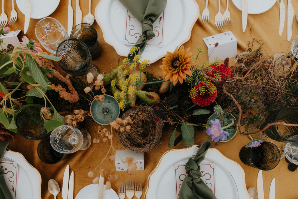 Overhead view of wedding table setting with handwritten menus, green napkins, and natural florals.