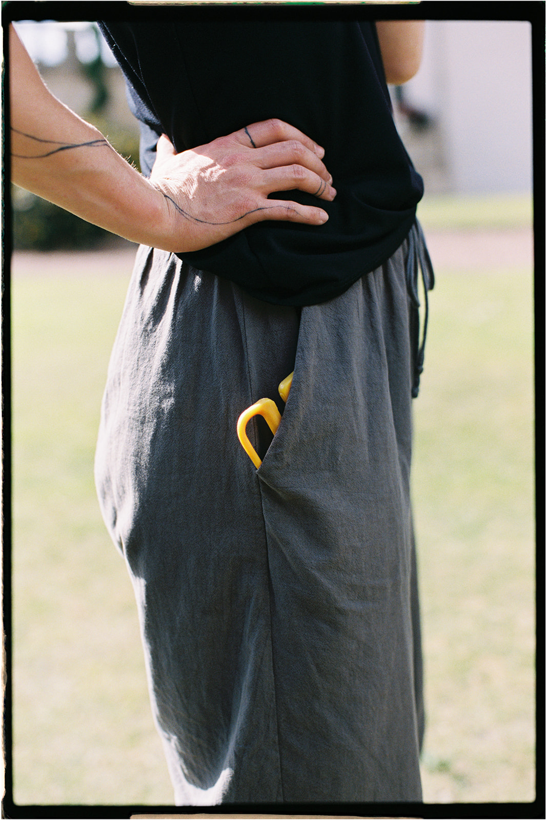 Florist standing outdoors holding yellow scissors while foraging foliage, photographed on 35mm film.